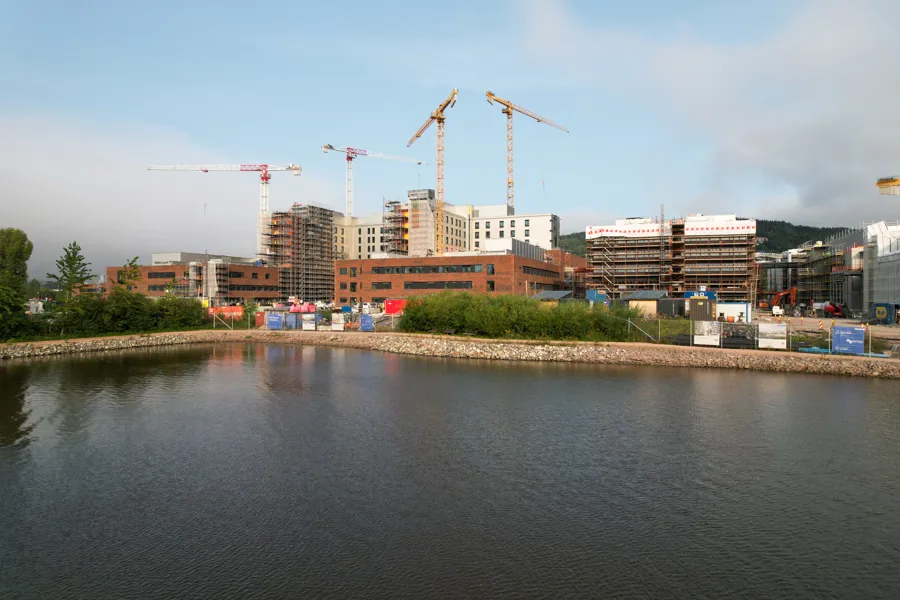 En vannmasse med bygninger og kraner i bakgrunnen