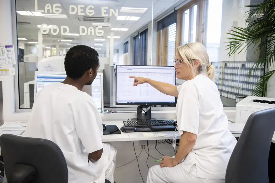 To ansatte i hvitt studerer informasjon på en pc