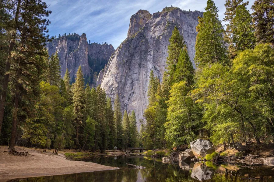 En elv med trær og fjell i bakgrunnen