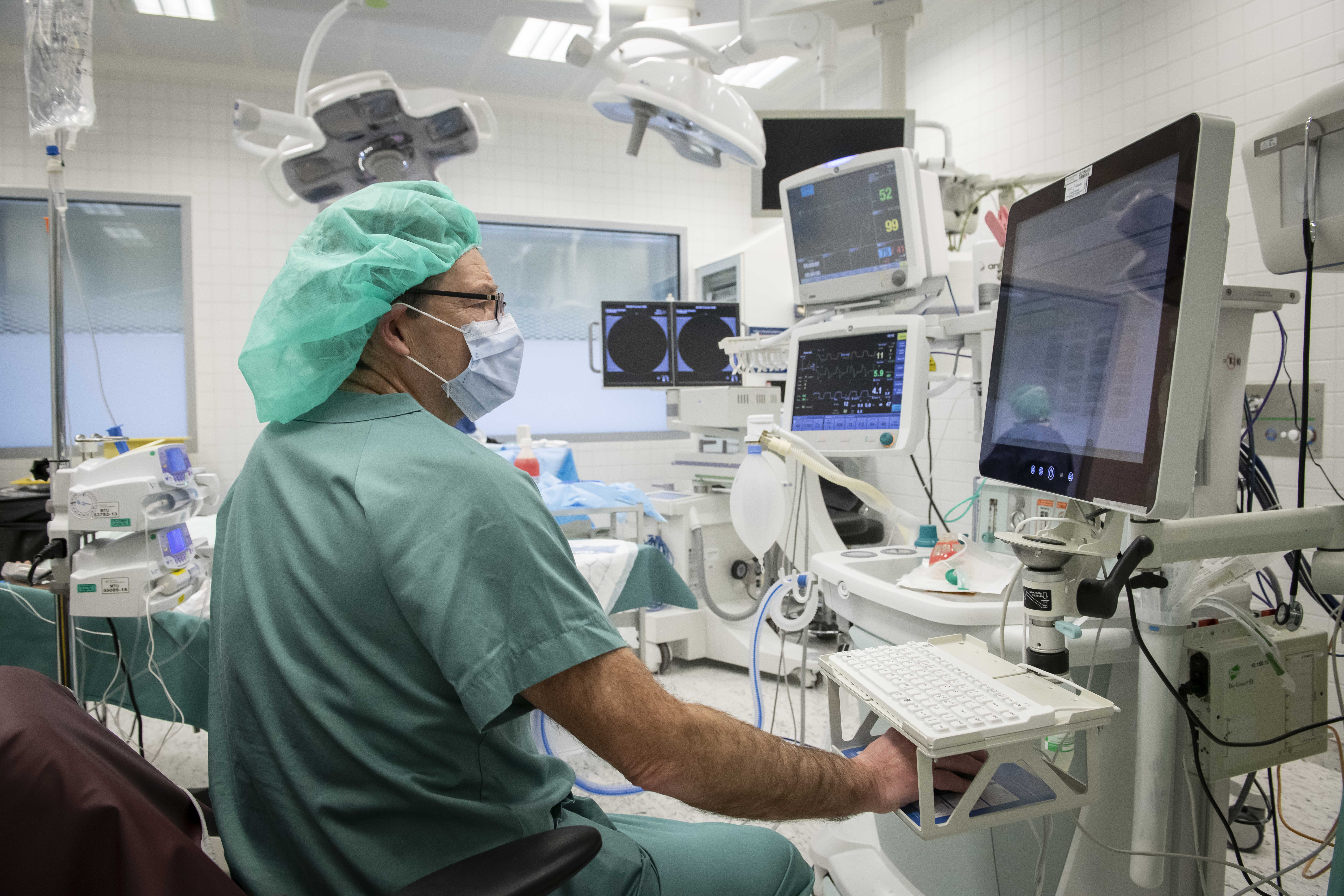 En mann i kirurgisk uniform i opperasjonssal med skjerm