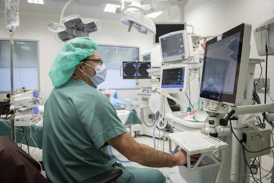 En mann i kirurgisk uniform i opperasjonssal med skjerm