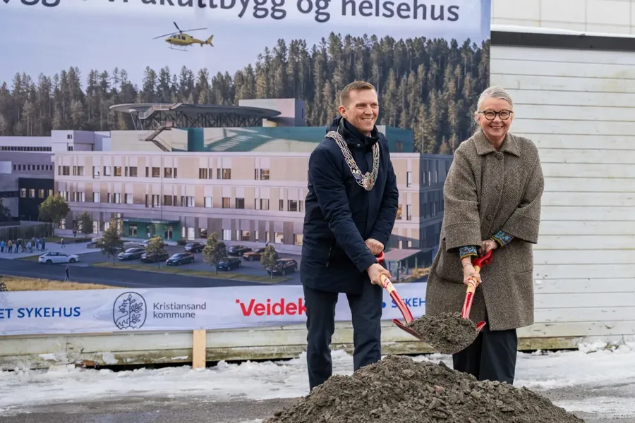 Ordfører og administrerende dør foran plansje av nytt sykehus med hver sin spade