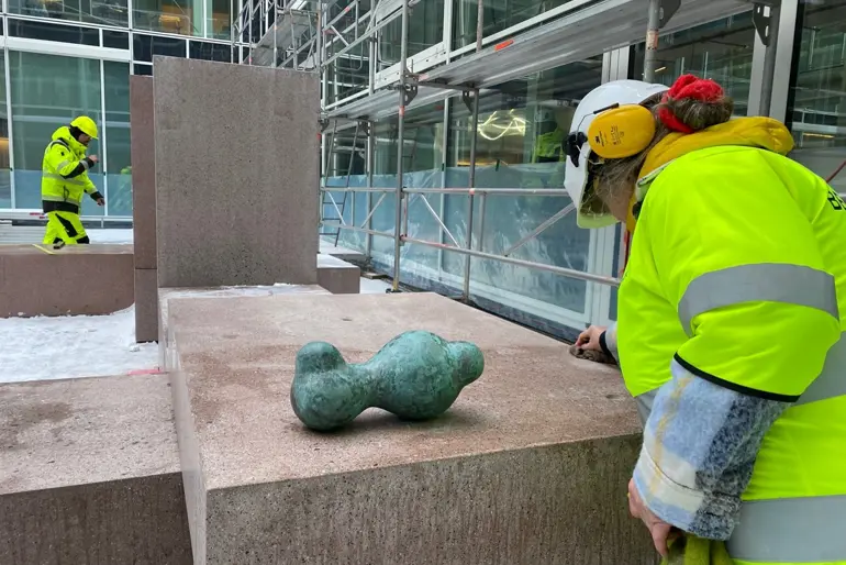 En gruppe brannmenn ser på en statue
