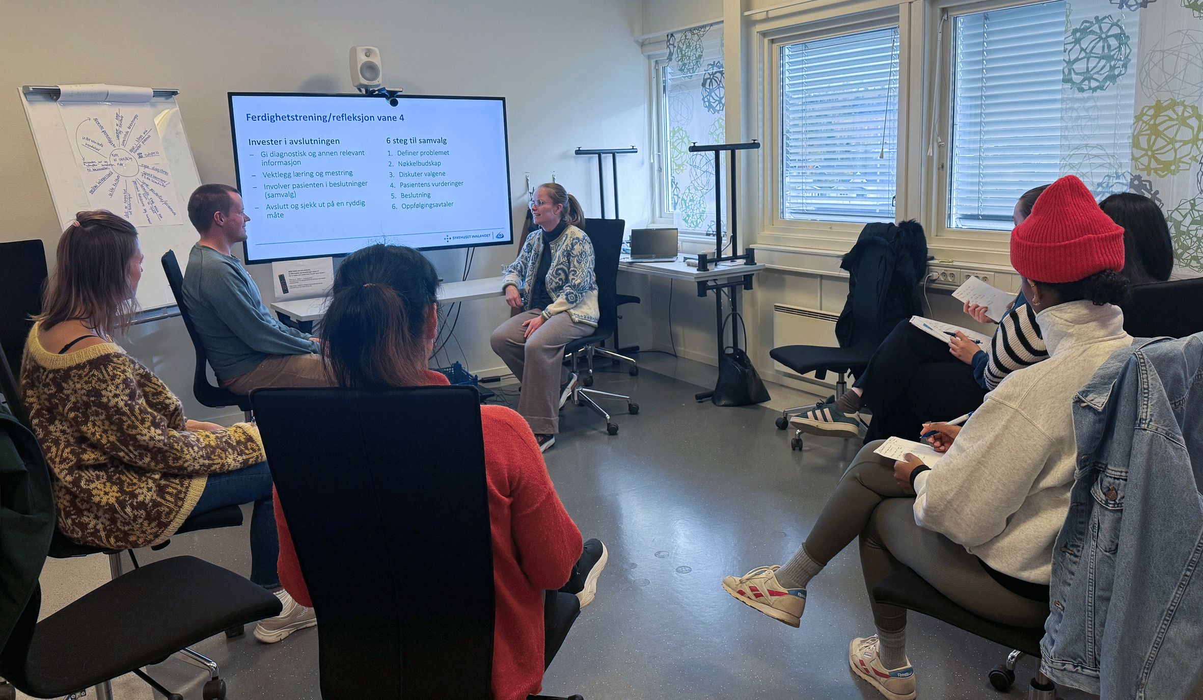 En gruppe mennesker som sitter i et rom og ser på en skjerm