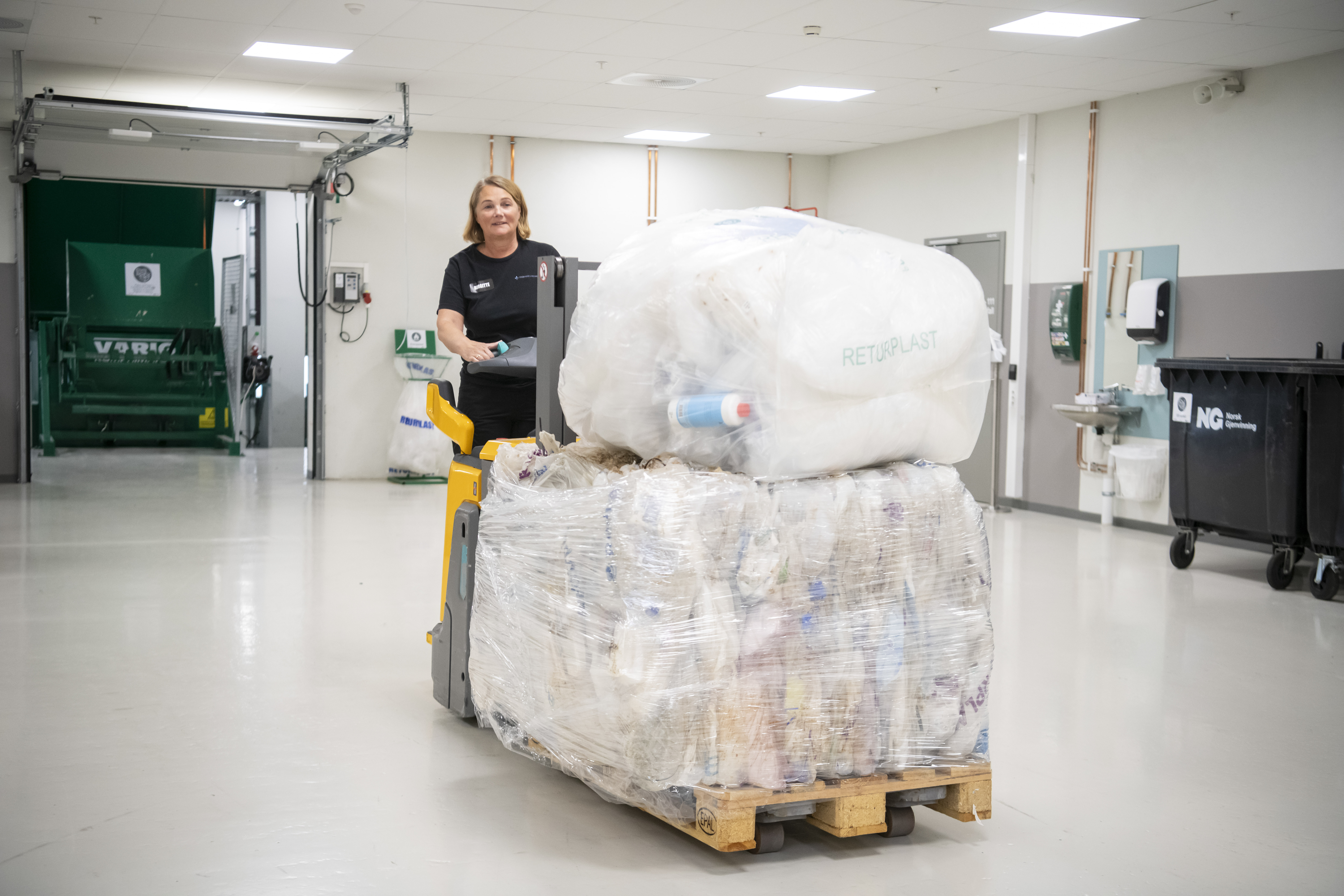 Dame på truck løfter pall med avfall