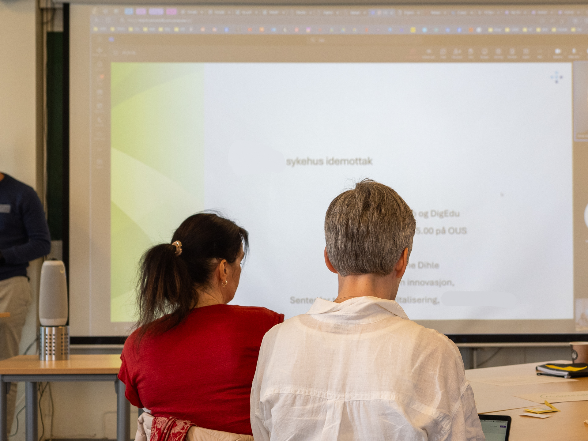 En mann og en kvinne som ser på et projisert bilde på en vegg