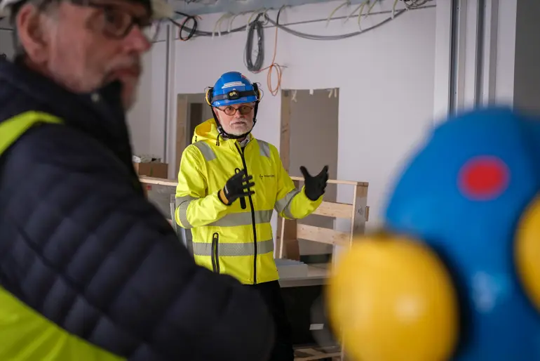 En mann i sikkerhetsvest og en mann i gul jakke