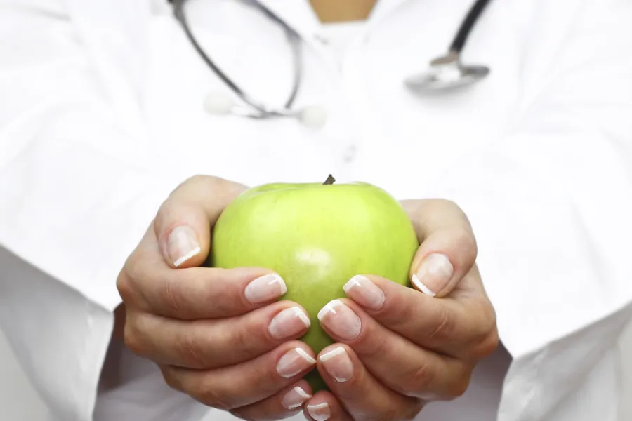 Hender som holder et grønt eple
