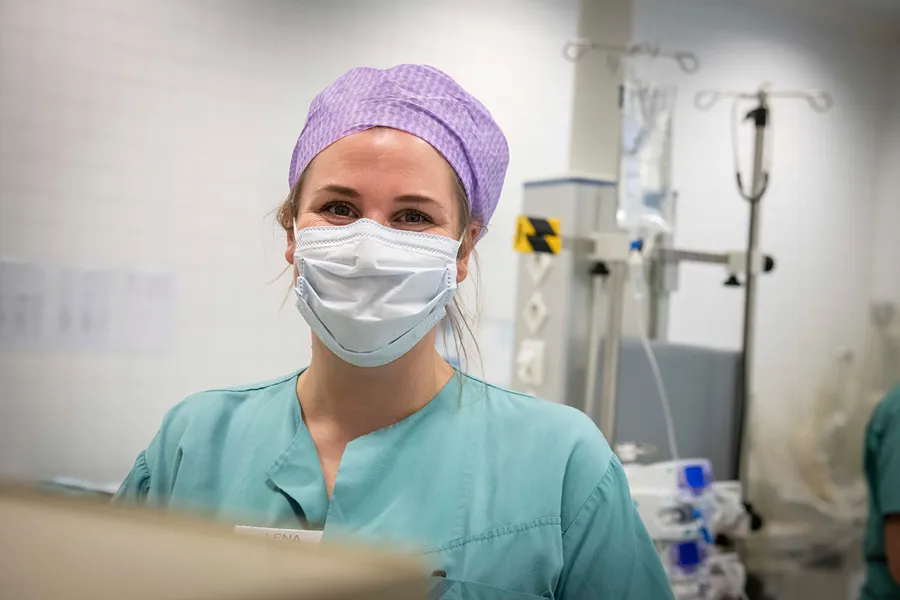 Bilde av opreasjonssykepleier med grønn skjorte, lilla hette og munnbind