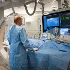 En kirurg i opreasjon med store skjermer