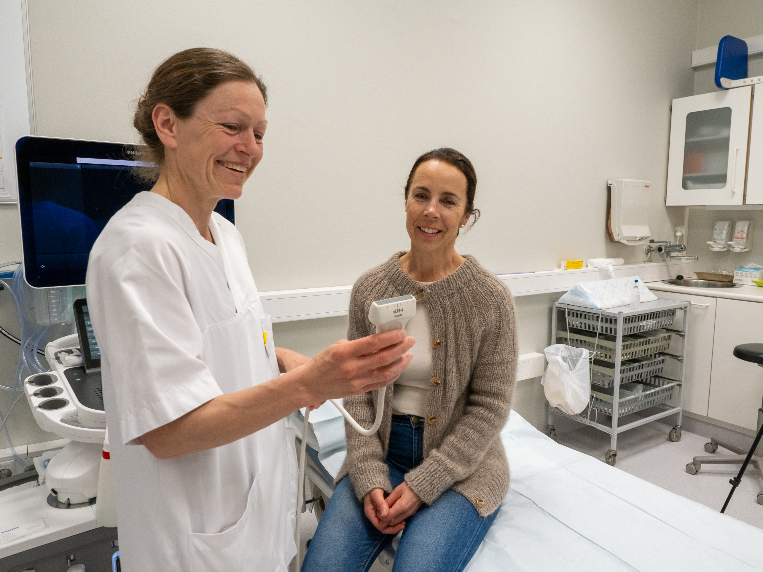 En lege som viser en pasient noe på nettbrettet