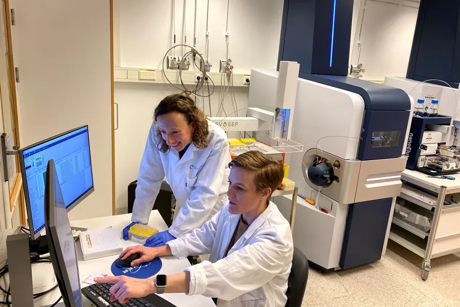 Et par personer i laboratoriefrakker som jobber med datamaskiner