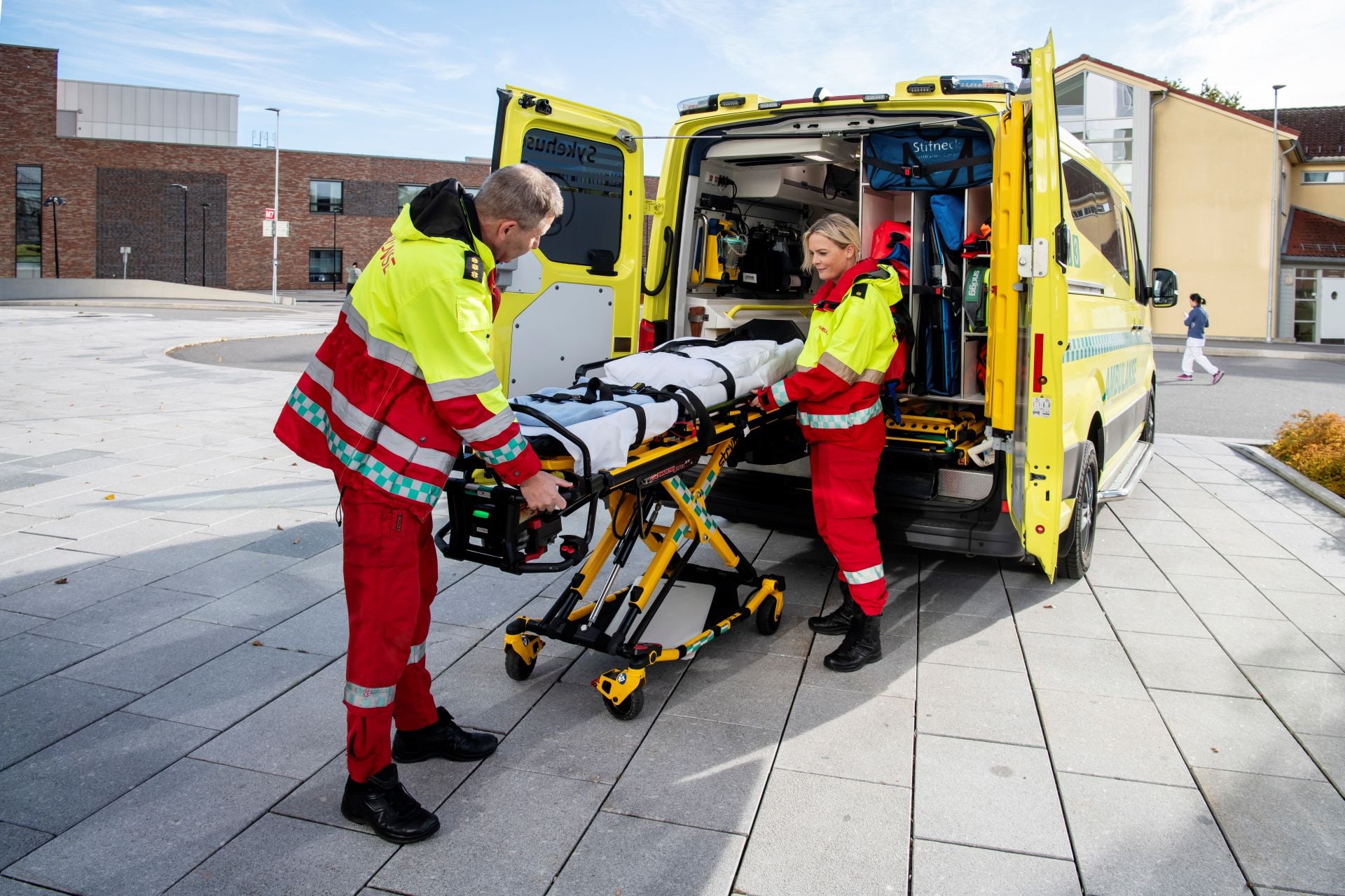 Noen menn i oransje dresser som jobber på en gul lastebil