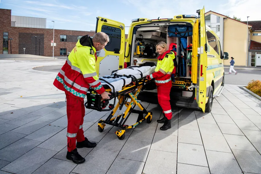 Noen menn i oransje dresser som jobber på en gul lastebil