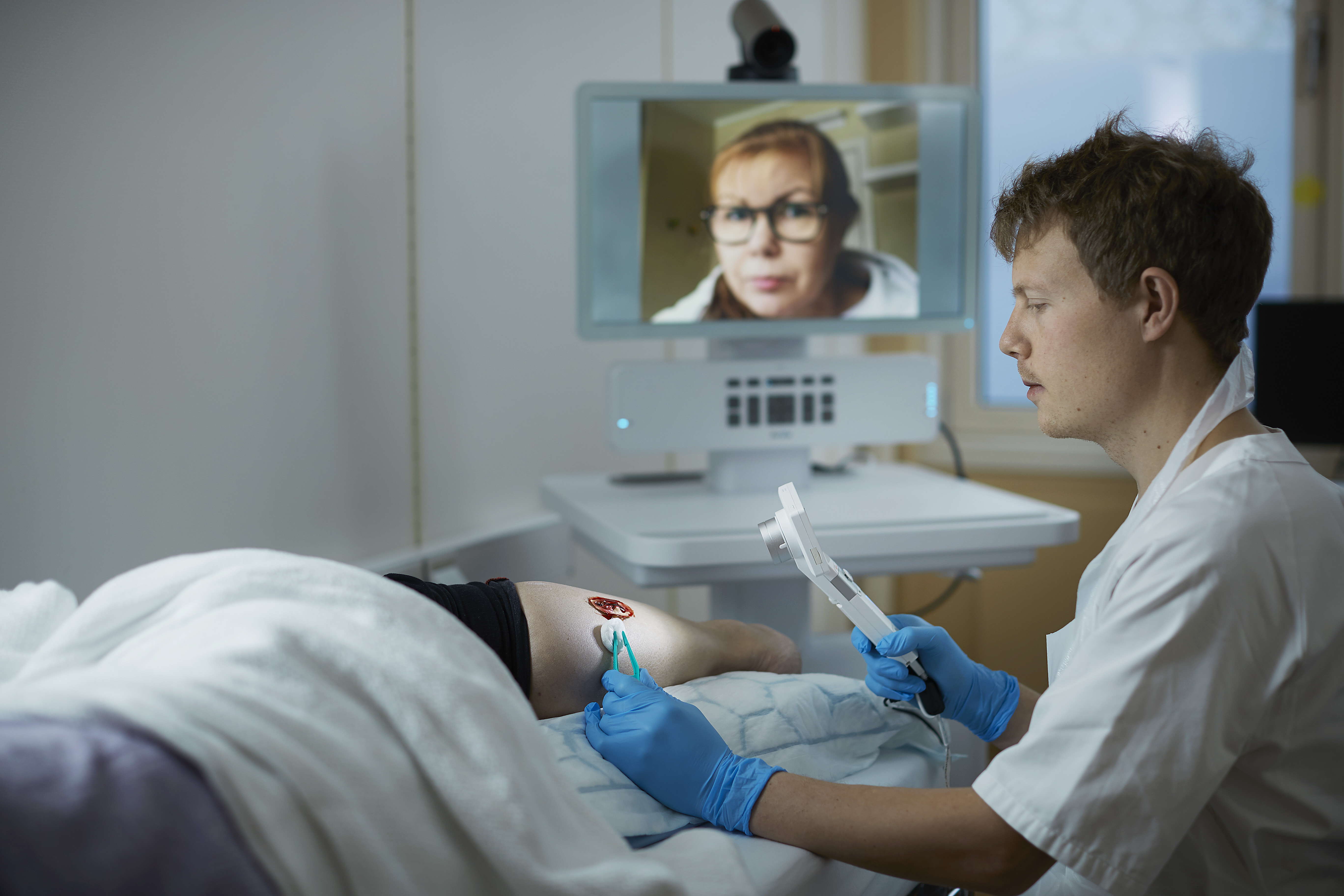 En sykepleier som blir veiledet av lege via video