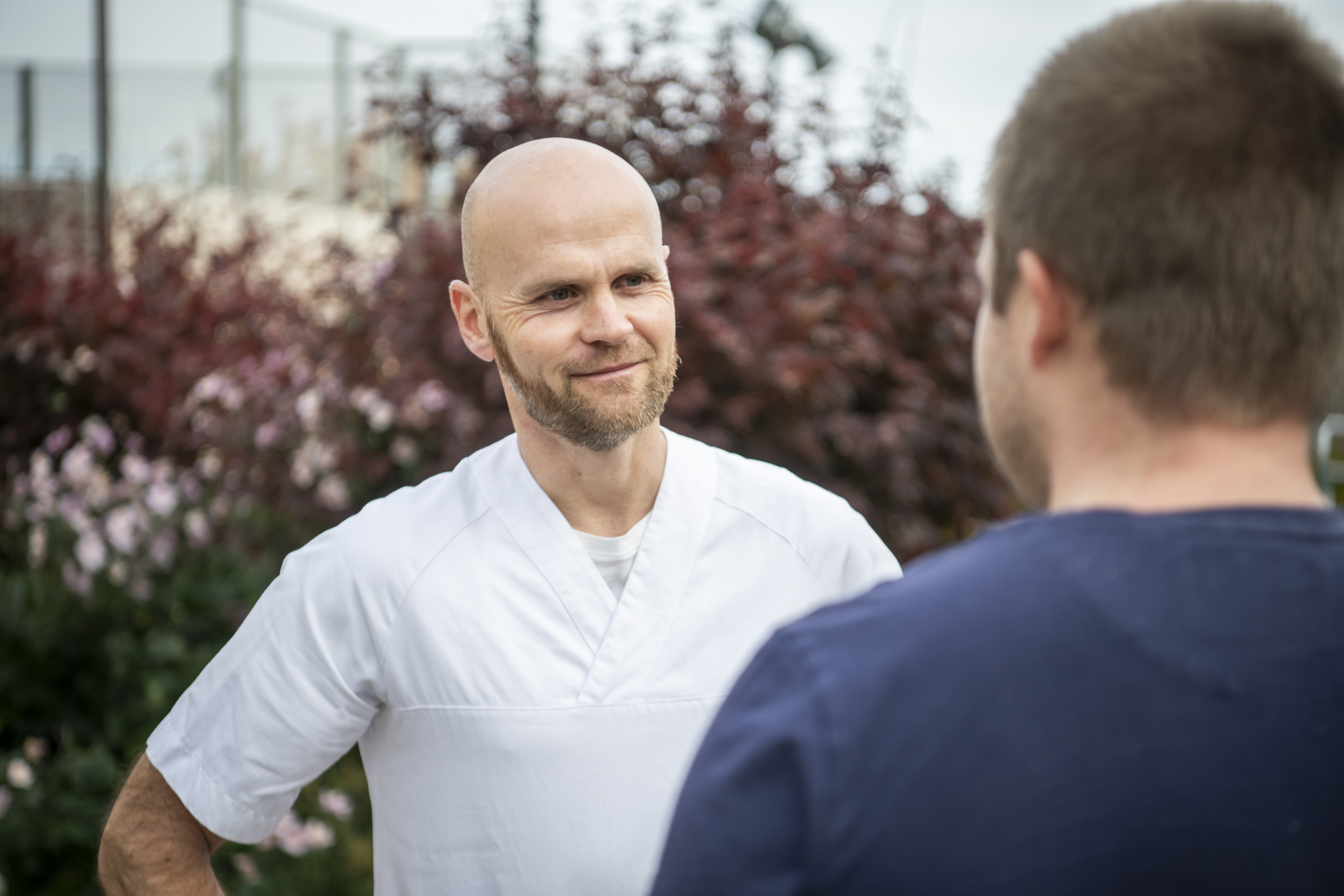 Hvitkledd ansatt i samtale med pasient utendørs