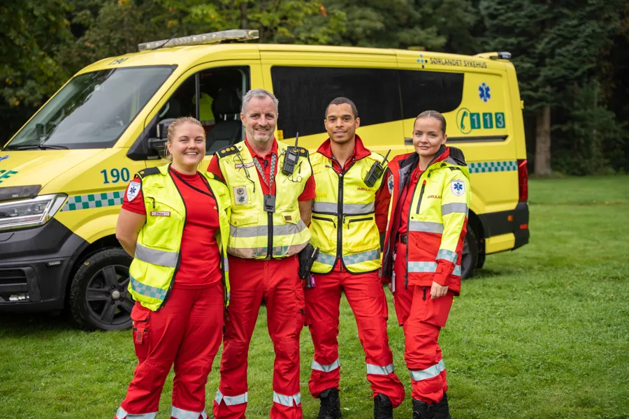 En gruppe menn i oransje vester som står foran en gul varebil