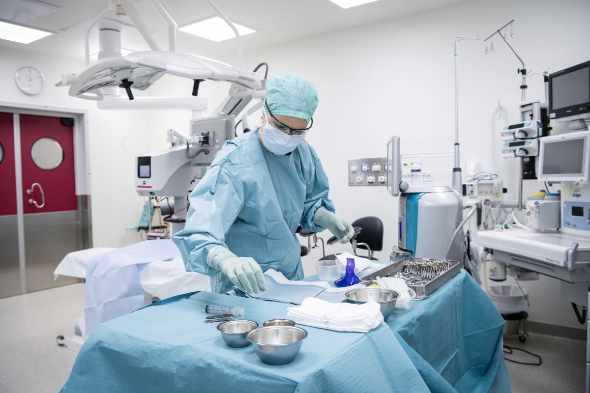 En person med kirurgisk maske og hansker i et rom med medisinsk utstyr