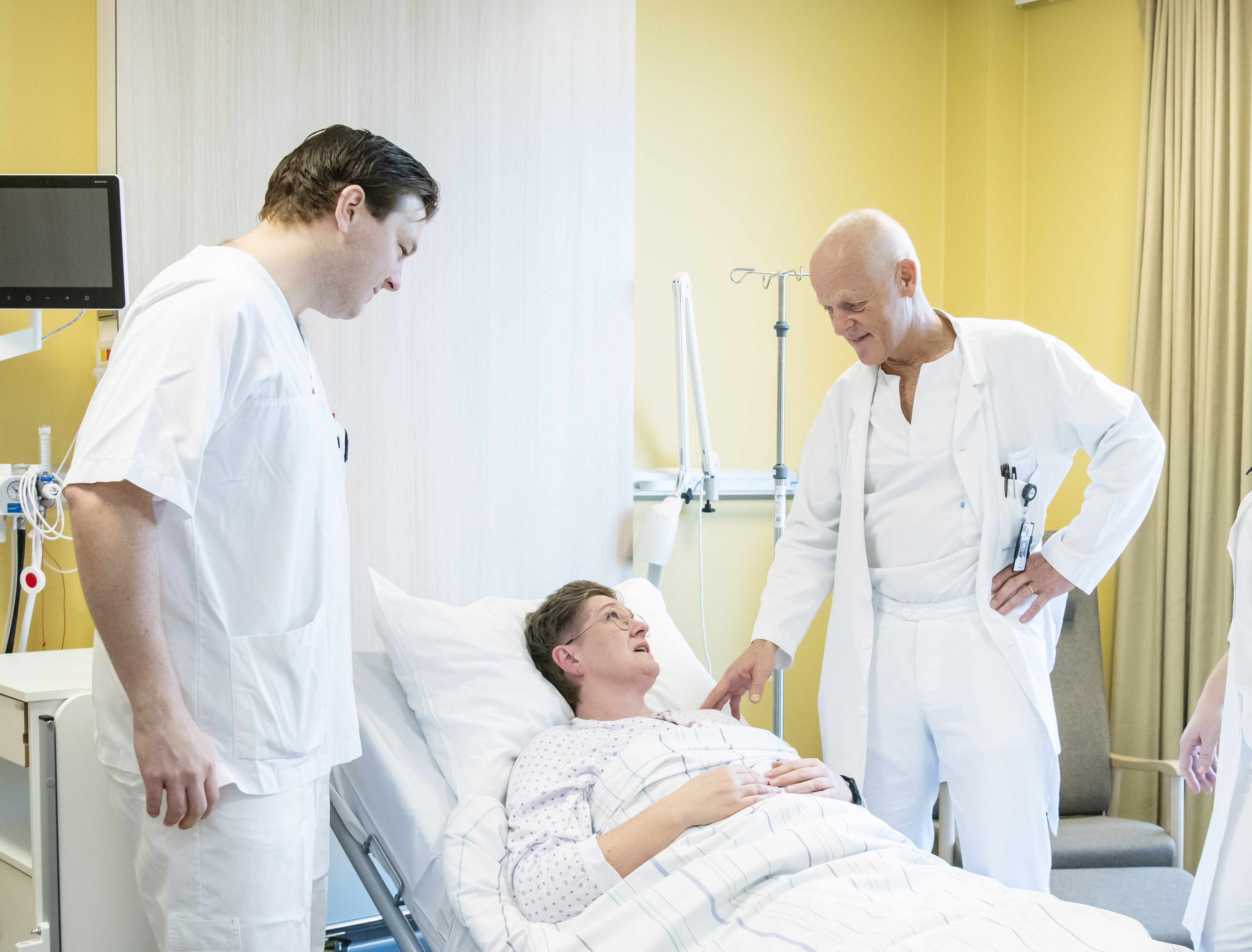 Helsepersonell står rundt en pasient i en sykehusseng