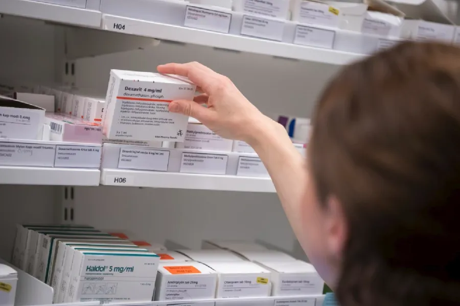 Kvinnelig helsearbeider henter legemidler på medisinrom