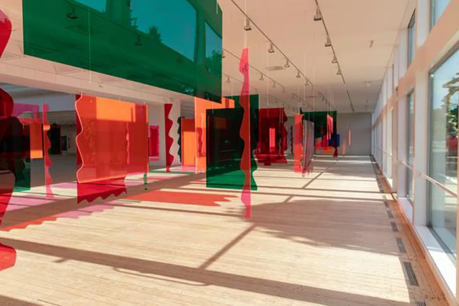 En lang gang med røde og grønne glass som henger fra taket