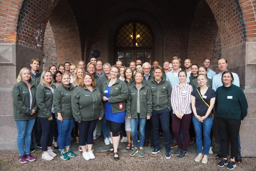 En gruppe mennesker som poserer for et bilde foran en murbygning