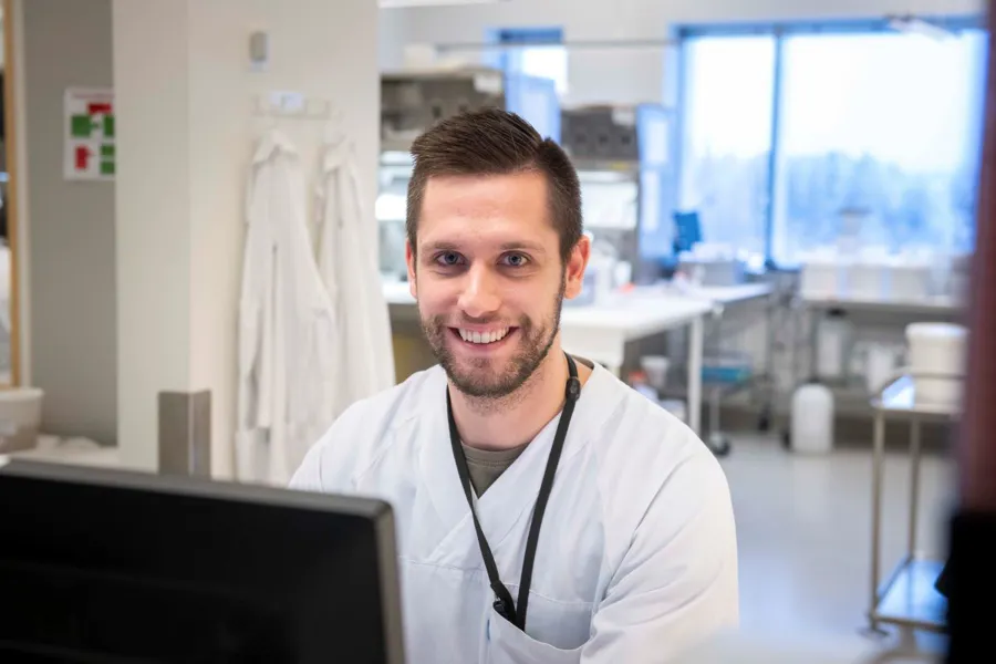 Lege sitter foran pc og smiler