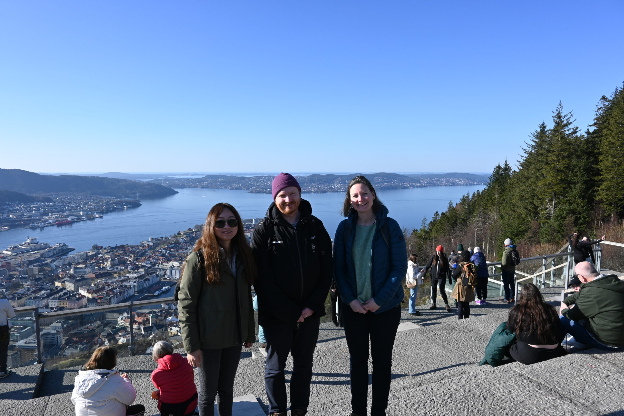En gruppe mennesker poserer for et bilde på en klippe over et vann
