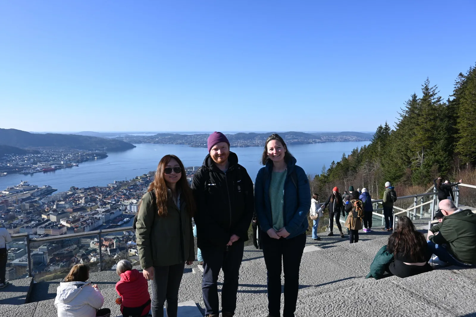 En gruppe mennesker poserer for et bilde på en klippe over et vann