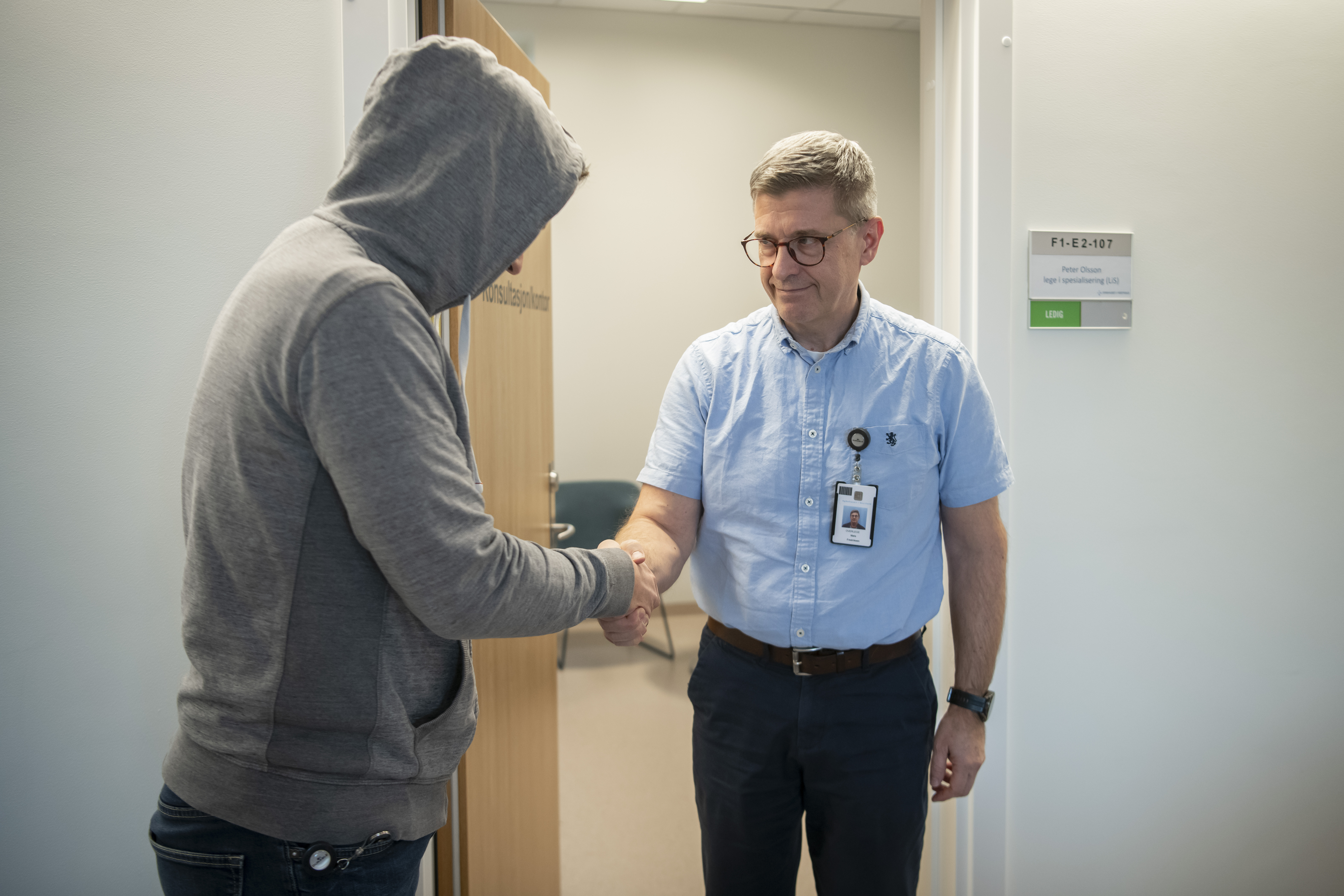 Gutt med hettegenser hilser på terapeut