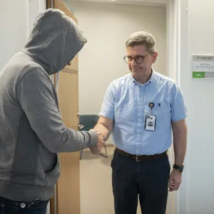 Gutt med hettegenser hilser på terapeut