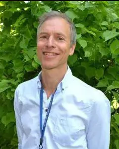 En mann som smiler foran en busk