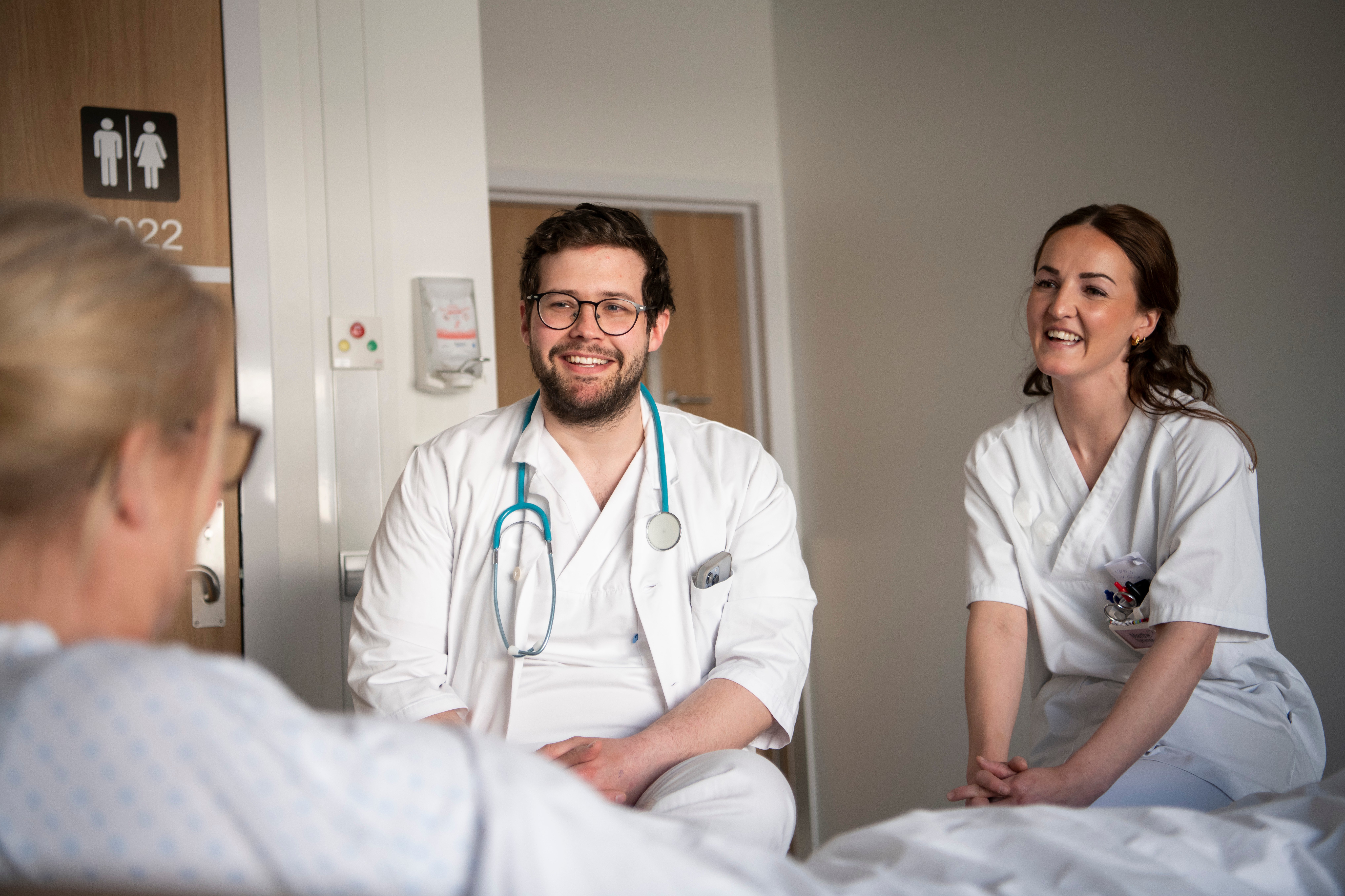 To ansatte i samtale med sengeliggende pasient