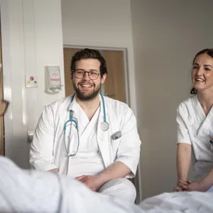 To ansatte i samtale med sengeliggende pasient