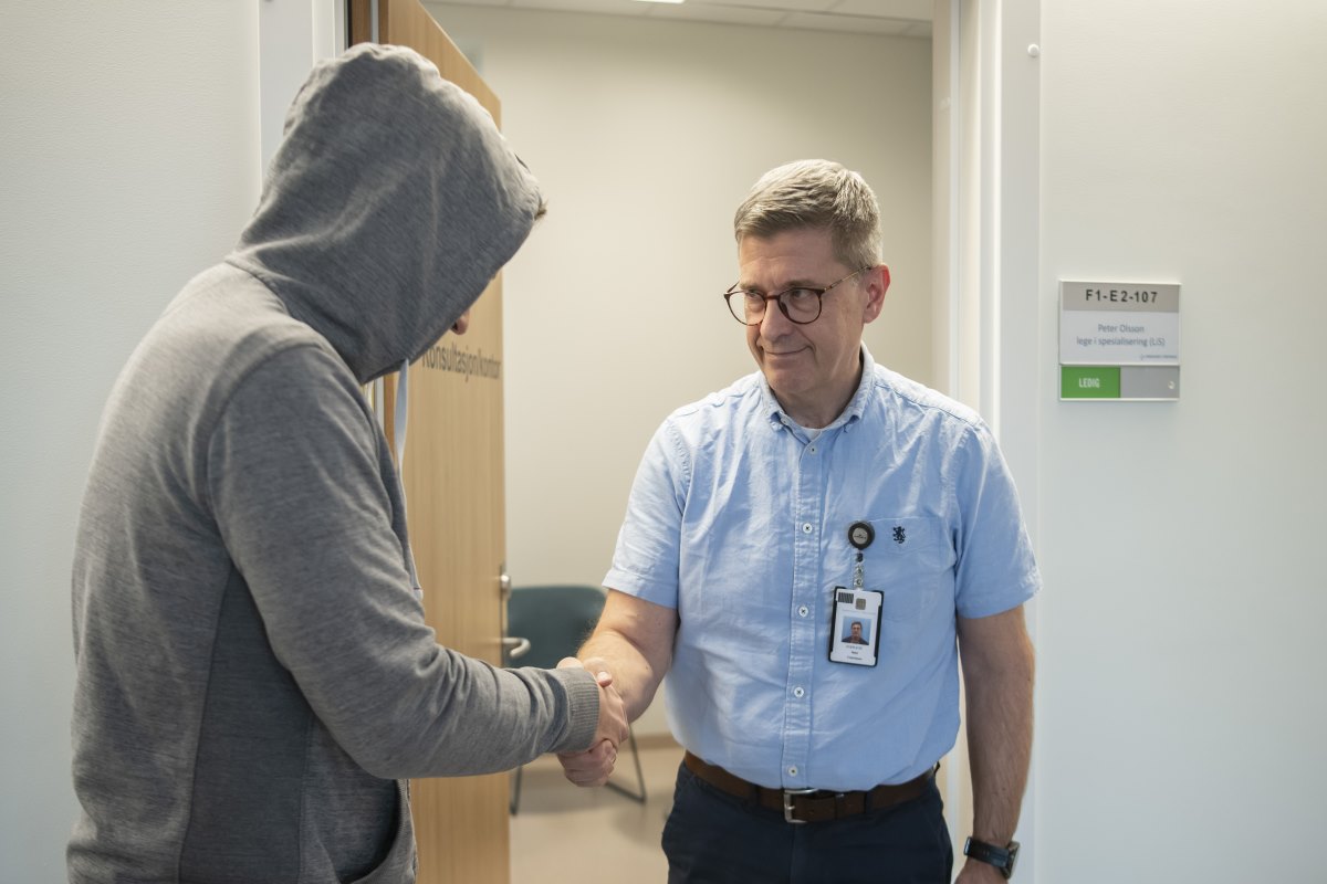 Pasient i hettegenser hilser på terapeut