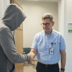 Pasient i hettegenser hilser på terapeut