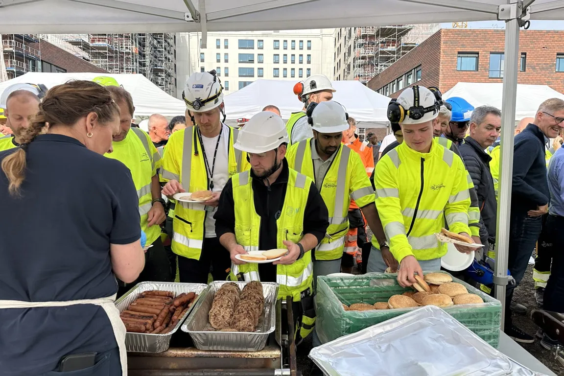 En gruppe mennesker i sikkerhetsvester som står rundt et bord med mat