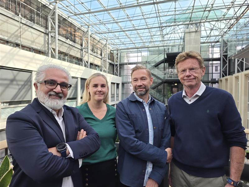En gruppe mennesker poserer for et bilde foran en glassbygning