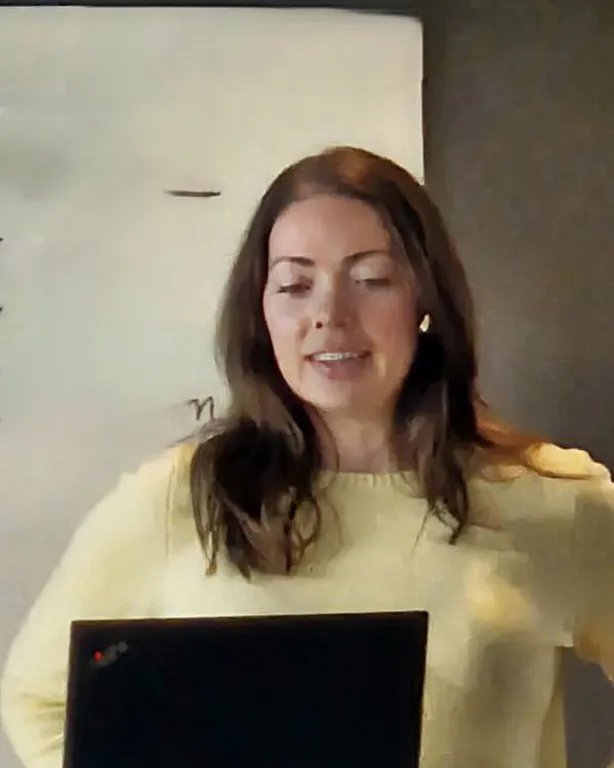 En person som smiler og ser på en bærbar PC