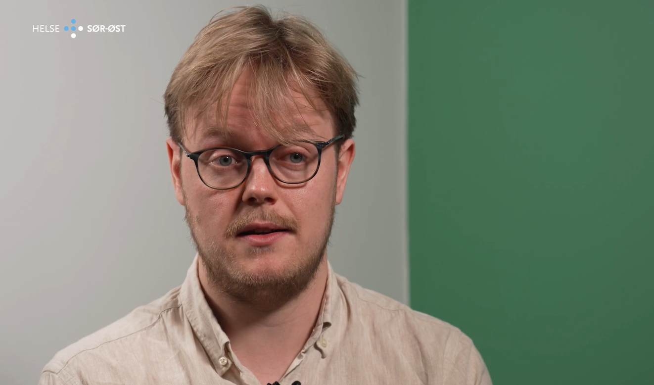 Mannlig lege med briller forteller om jobben sin.