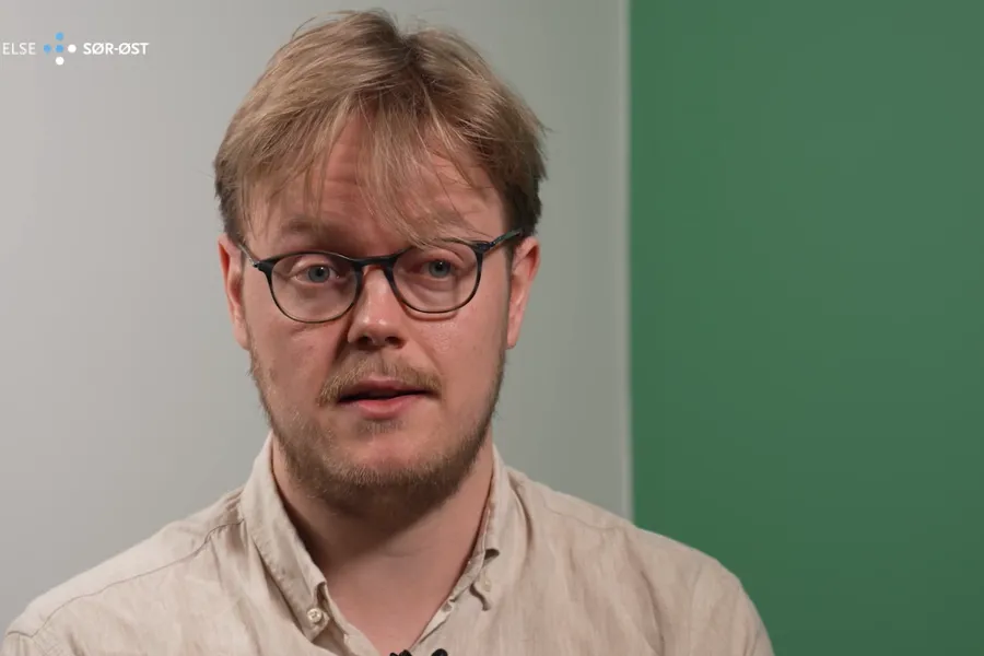 Mannlig lege med briller forteller om jobben sin.