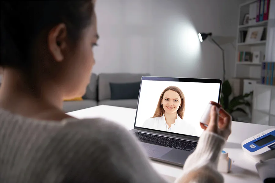 Pasient ved PC som får digital oppføling hjemme, legen sees på skjermen