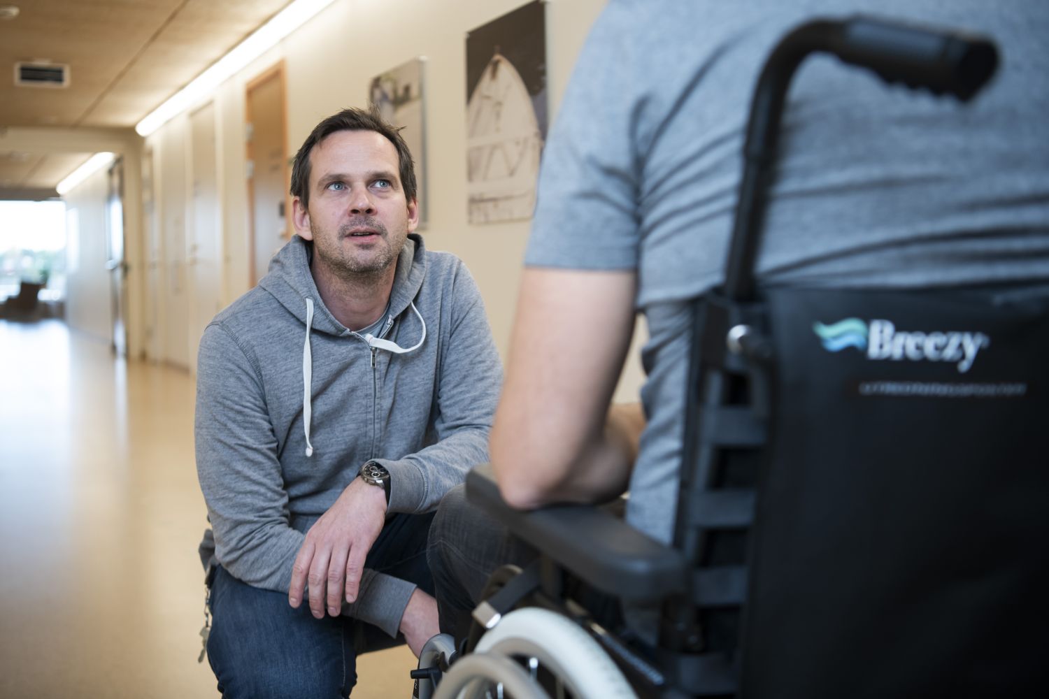 Behandler sitter foran person i rullestol