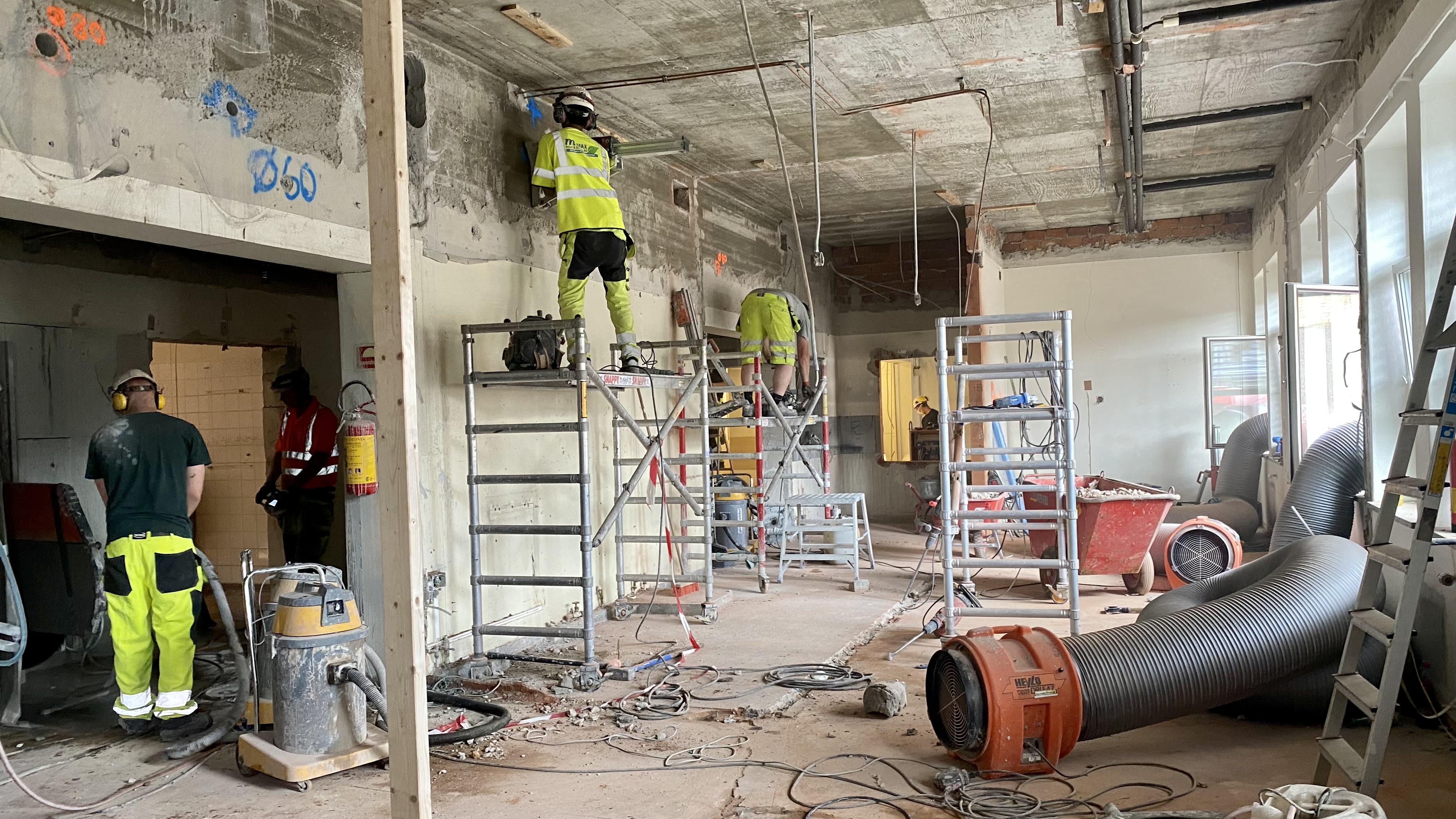 En gruppe menn i gule uniformer som står i et rom med stiger