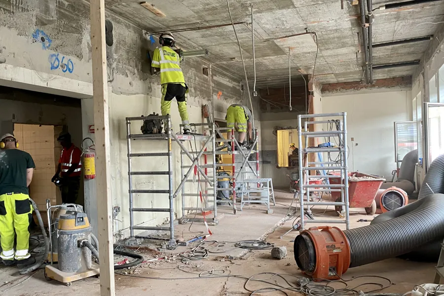 En gruppe menn i gule uniformer som står i et rom med stiger