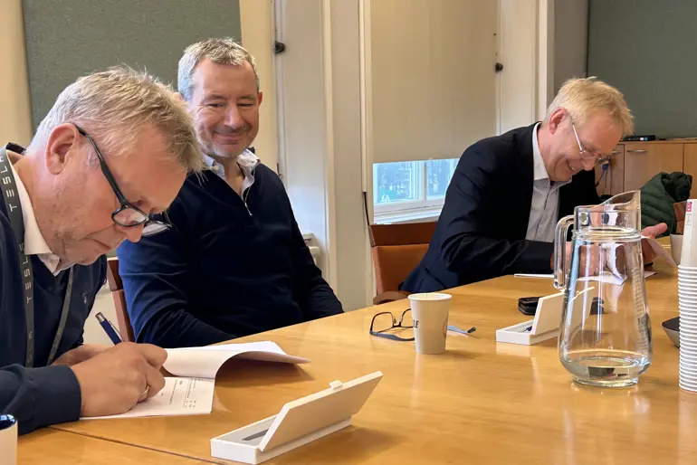 En gruppe menn som sitter ved et bord og ser på papirer