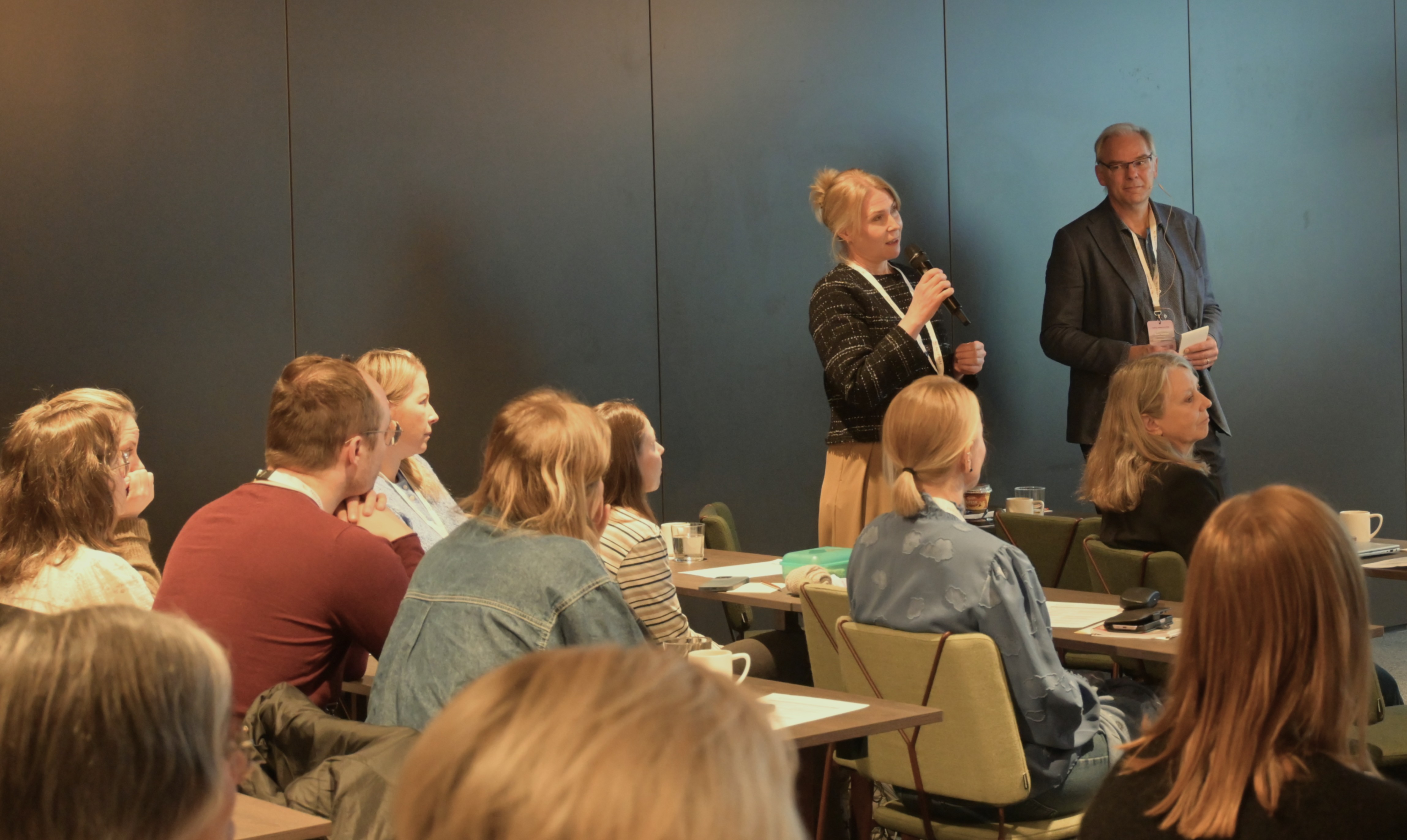 En mann og en kvinne står foran en gruppe mennesker