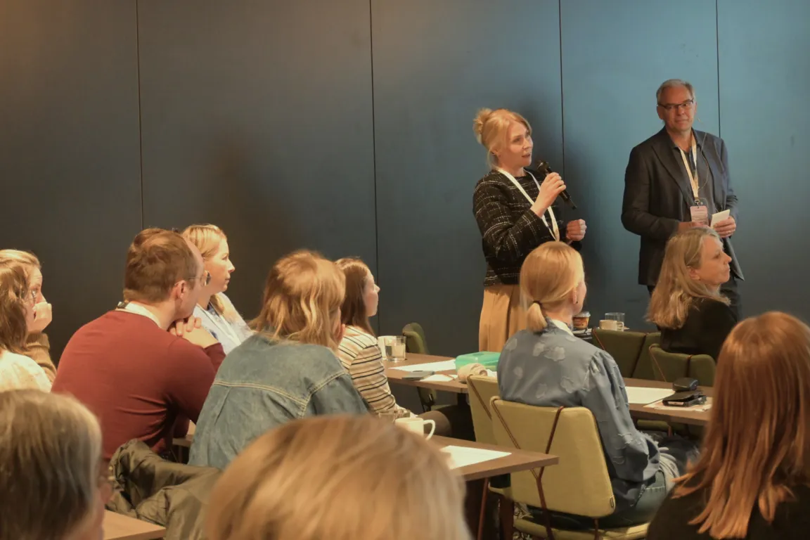 En mann og en kvinne står foran en gruppe mennesker