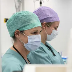 To ansatte med med opperasjonsluer og munnbind