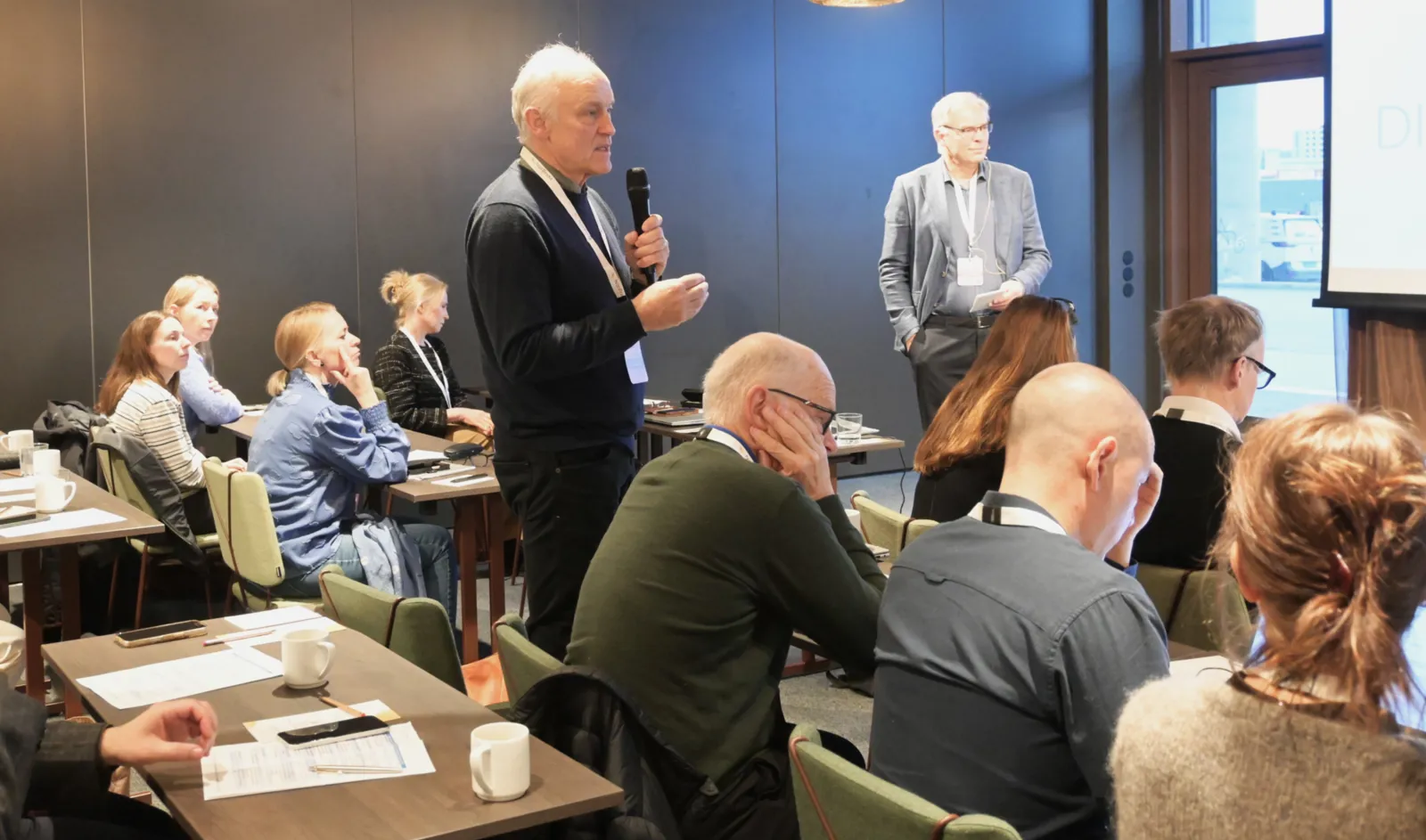 En person som snakker til en gruppe mennesker i et rom